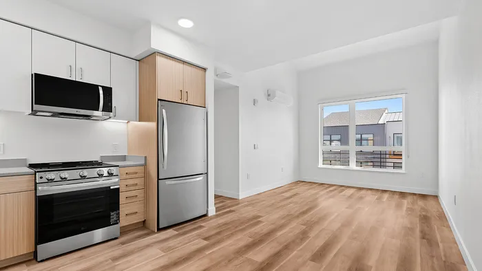 Sleek modern kitchen with stainless steel appliances and spacious living area with large window for natural light.
