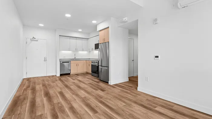 Modern apartment showcasing a stylish kitchen with stainless steel appliances, sleek cabinetry, and elegant wood flooring.