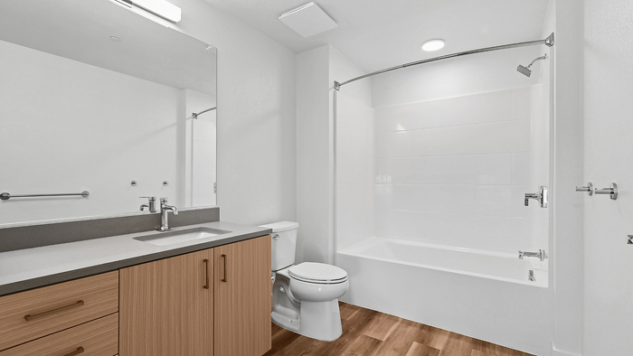 Modern bathroom design with sleek wooden cabinetry, pristine white countertop, and a spacious bathtub.