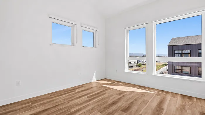 Bright and airy room with large windows offering scenic views, accented by elegant wood flooring.