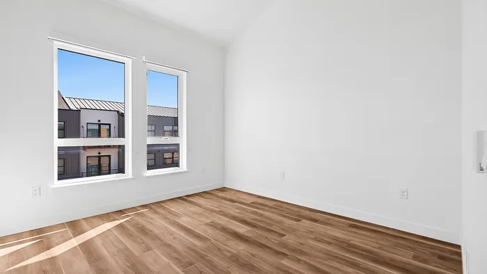Bright and airy room featuring elegant hardwood floors and large windows with scenic city views.