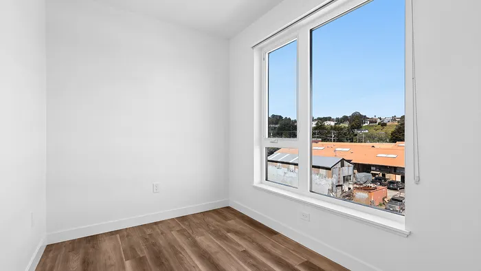 Bright room with large window showcasing a scenic view, featuring elegant wood flooring and fresh white walls.
