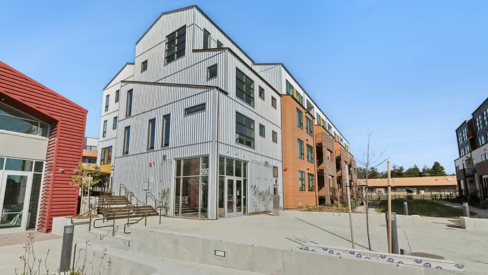 Modern architectural apartment complex with sleek metal siding and large windows, offering stylish urban living with convenient access.