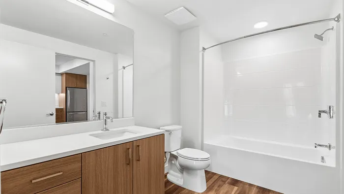 Modern bathroom with sleek wooden cabinetry, a spacious tub, and elegant lighting, offering a serene retreat.