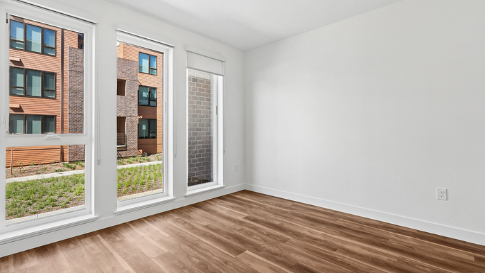 Bright and airy room with large windows, offering a serene view of a modern building, perfect for natural light lovers.