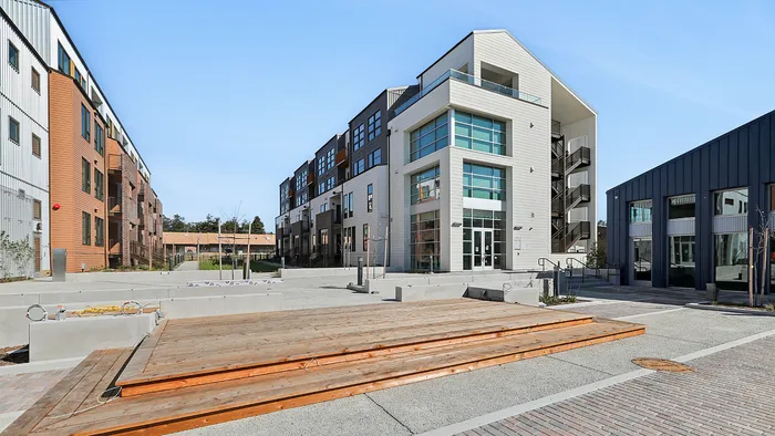 Modern apartment complex with stylish wooden and metal facades, featuring expansive glass windows for natural light.