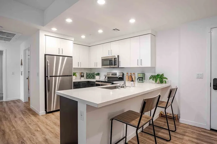 Modern kitchen with sleek stainless steel appliances, elegant white cabinetry, and a spacious island with seating, offering a perfect blend of style and functionality.