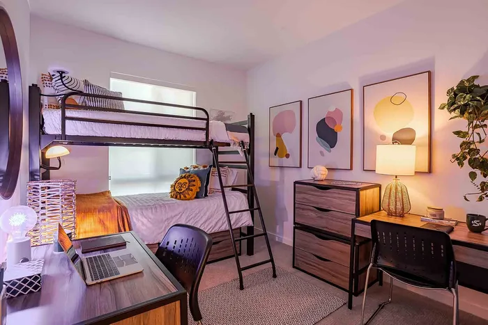 Inviting bedroom with modern bunk beds, stylish decor, and a cozy workspace exuding charm and functionality.