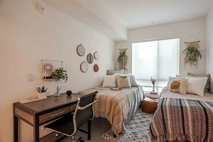 Inviting bedroom with stylish decor, featuring two cozy beds, a charming desk setup, and lush indoor plants.