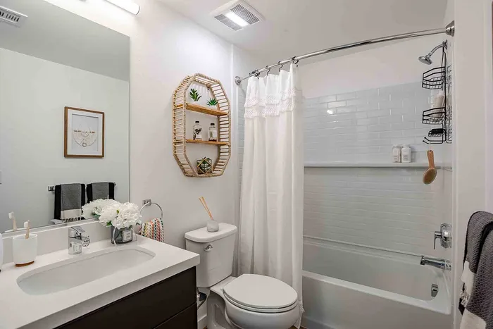Elegant bathroom boasting modern fixtures, stylish wicker shelving, and a serene white shower curtain for a spa-like ambiance.