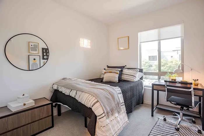 Bright and cozy bedroom with stylish decor, featuring a comfortable bed, modern desk, and large window letting in natural light.