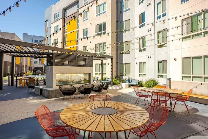 Modern apartment courtyard featuring stylish outdoor seating, string lights, and contemporary architecture, perfect for social gatherings.