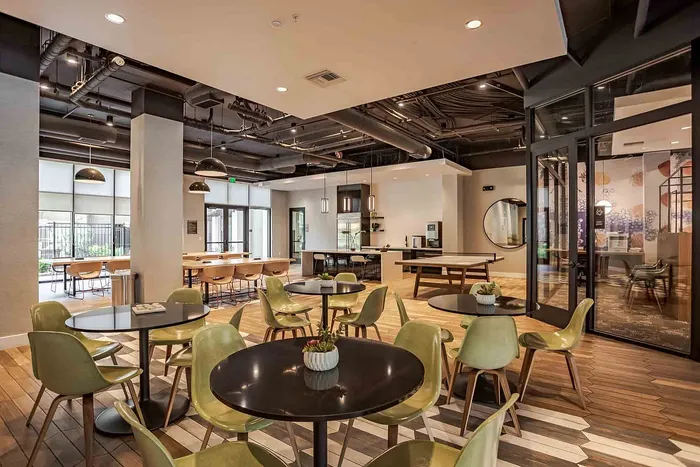 Modern communal space featuring sleek dining tables and stylish chairs, blending open-concept design with chic industrial aesthetics.