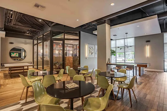 Modern communal space with stylish seating, wooden flooring, natural light, and a chic design for relaxed gatherings.