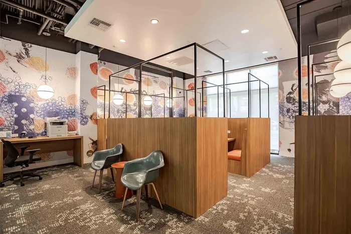 Modern co-working space featuring stylish wooden workstations, vibrant artwork, and cozy seating for creative collaboration.