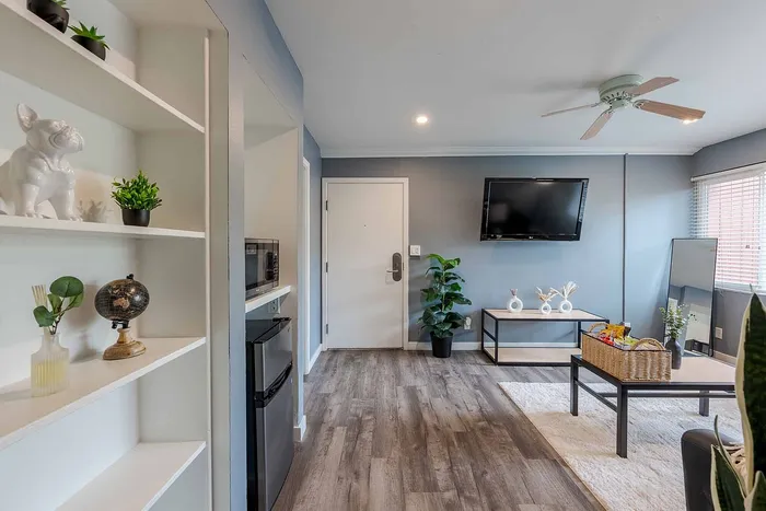 Inviting living area with stylish decor, featuring built-in shelving, elegant wood flooring, and modern entertainment setup.