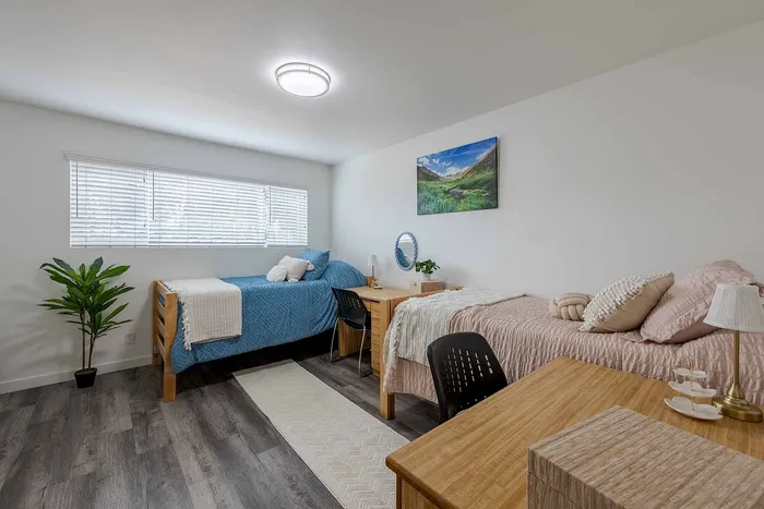 Bright and inviting bedroom with cozy twin beds, stylish decor, and abundant natural light from large window.