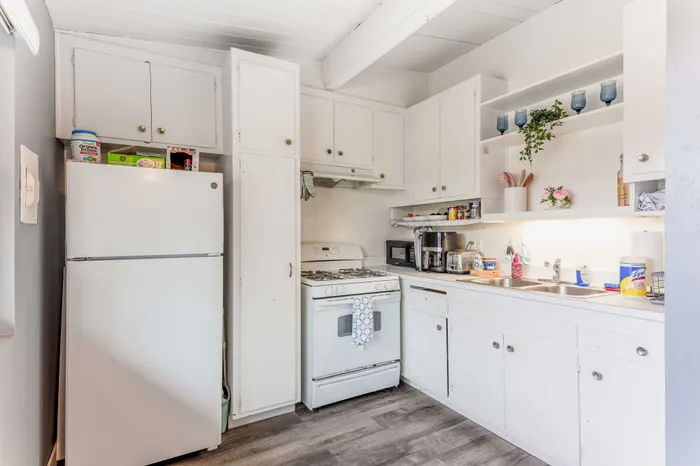 Bright and inviting kitchen with modern appliances, sleek white cabinetry, and open shelving for a stylish touch.
