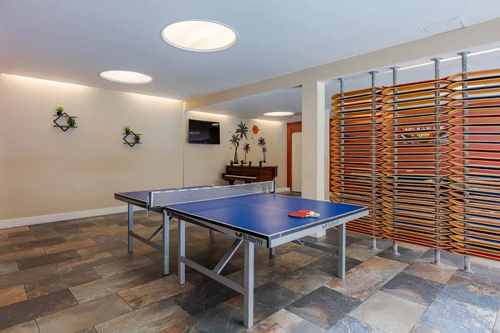 Modern recreational room featuring a ping pong table, elegant decor, and a cozy piano corner.