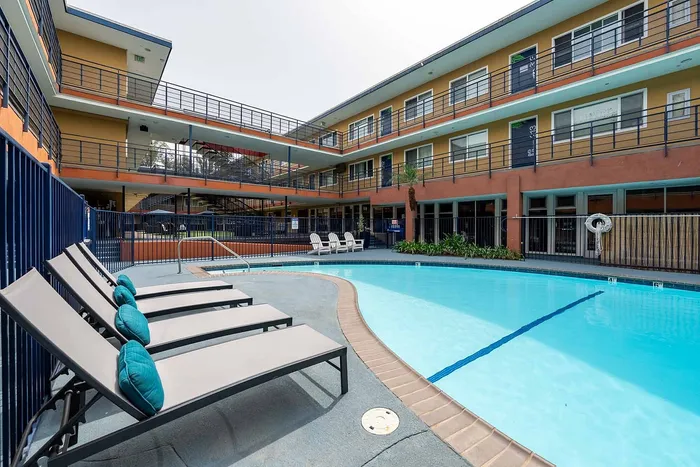 Chic apartment complex featuring a sparkling outdoor pool with comfortable lounge chairs, ideal for relaxation and socializing.