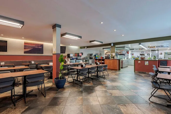 Inviting cafeteria featuring modern seating, ambient lighting, and a well-equipped kitchen area.