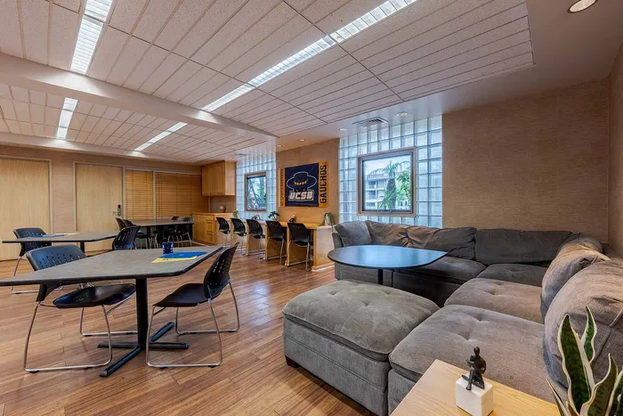 Modern and inviting communal area featuring cozy sectional seating, sleek tables, and vibrant natural light.