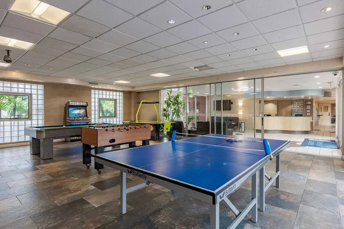 Vibrant recreation room featuring a ping pong table, foosball, and billiards with modern decor and ample natural light.