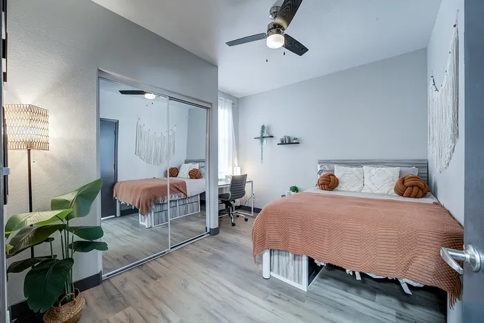 Chic bedroom featuring cozy decor with a soft orange throw, large mirrored closet, and elegant wall art, perfect for a modern lifestyle.