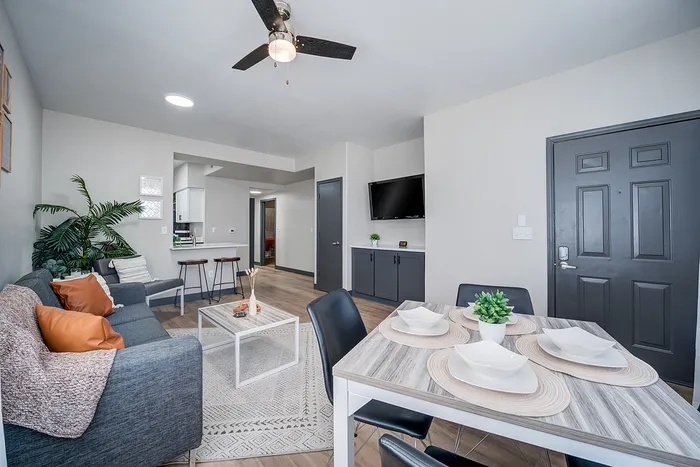 Inviting modern apartment interior featuring a bright living room with a stylish sofa, open-concept dining area, and sleek kitchen bar.