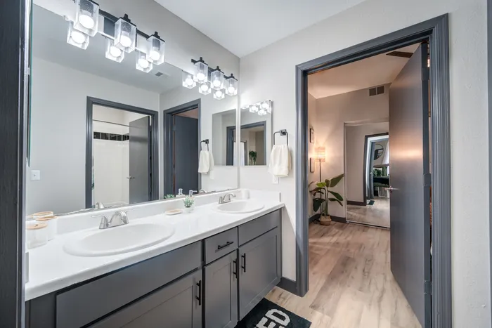 Modern bathroom with elegant double sinks, stylish lighting, and inviting hallway view adding luxury and comfort.