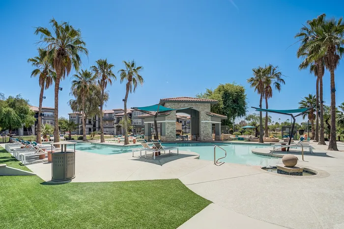 Luxurious outdoor pool area with palm trees and sun loungers, ideal for relaxation and leisure in a vibrant residential community.