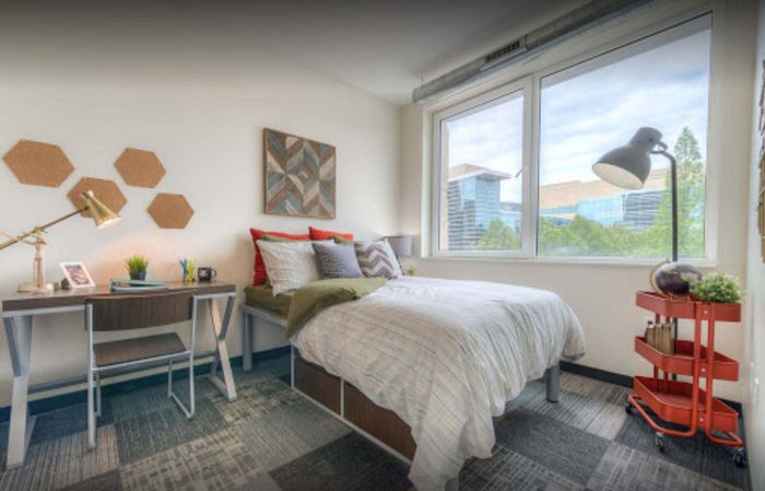 Bright and inviting bedroom with modern desk and large window offering lush greenery views, ideal for relaxation and inspiration.