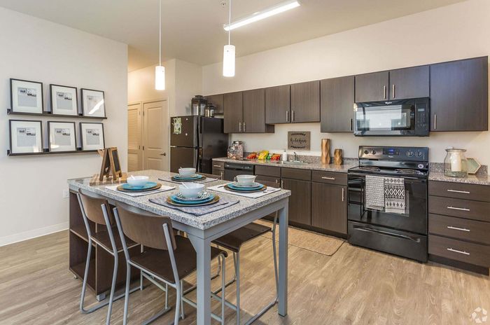 Contemporary kitchen featuring sleek dark cabinetry, spacious granite countertops, and a stylish island with seating for four. Modern appliances and unique decor complete the inviting space.