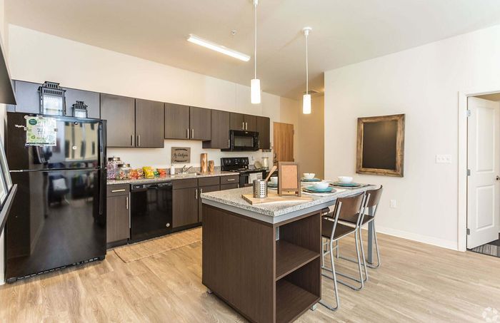 Modern kitchen design featuring sleek dark cabinetry, granite countertops, and an inviting breakfast island with stylish seating.