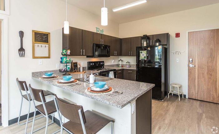Modern kitchen with granite countertops, stylish bar seating, and sleek dark cabinetry, perfect for entertaining.