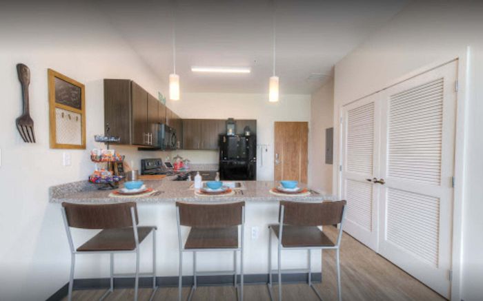 Modern kitchen with sleek dark cabinets, a spacious granite breakfast bar, and elegant pendant lighting, perfect for comfort and style.