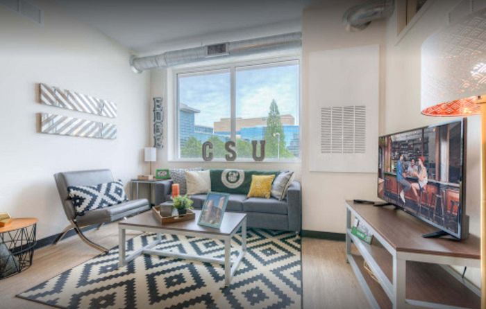 Bright and cozy living room with modern furniture, large window view, stylish decor, and flat-screen TV.
