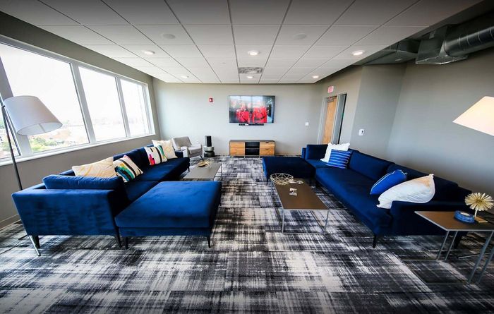 Modern living room with sleek blue sectional sofas, cozy pillows, and a contemporary design, perfect for relaxation and entertainment.
