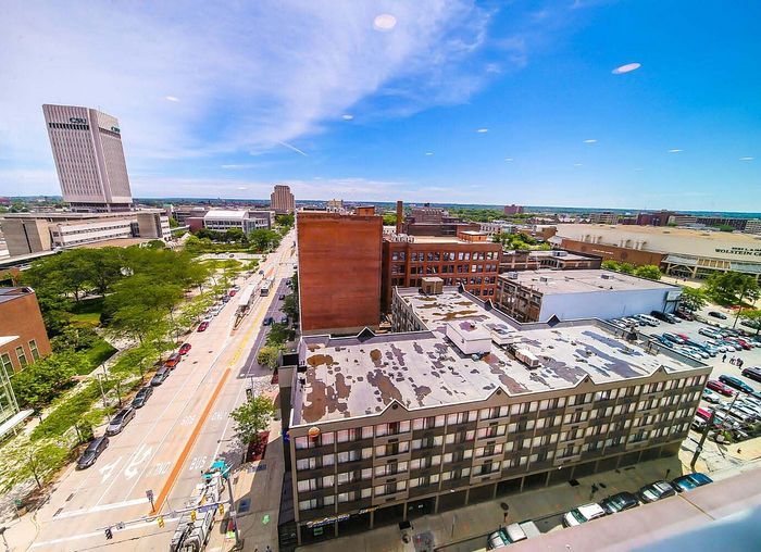 Vibrant cityscape view from above, showcasing modern architecture and lush green spaces under a clear blue sky.