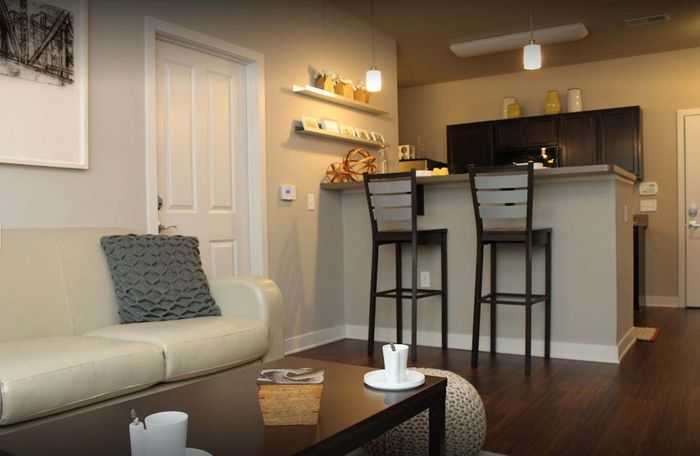 Cozy living room with elegant decor, featuring a plush beige sofa, sleek coffee table, and a chic breakfast bar with stylish seating.
