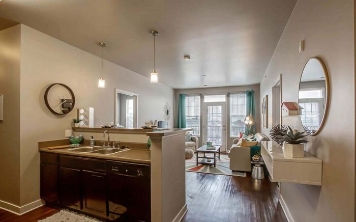 Chic open-plan living space with modern kitchen and cozy seating area, featuring stylish decor and ample natural light.