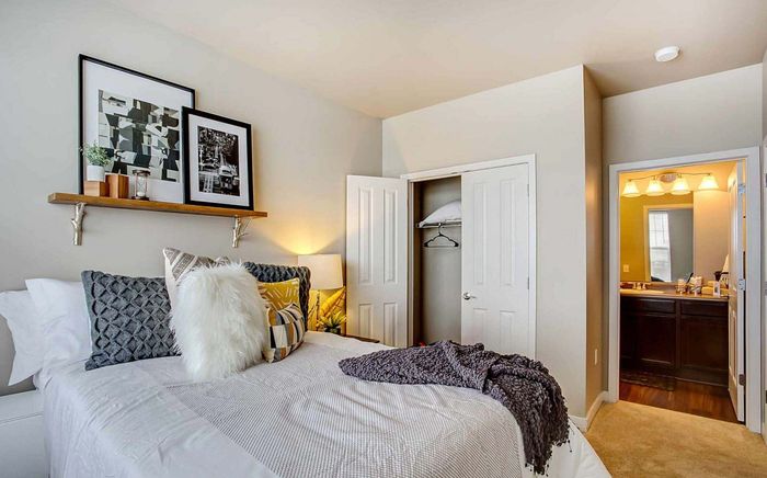 Cozy bedroom with modern decor, plush bedding, and stylish wall art, leading to an elegant en-suite bathroom.
