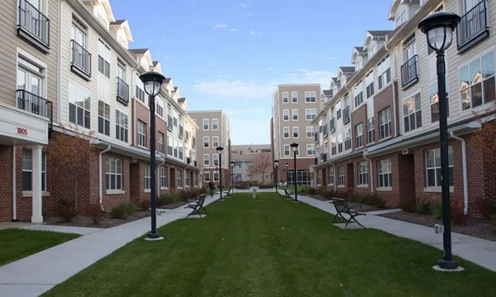 Charming apartment complex with modern architecture, picturesque lawn, and inviting open courtyard seating, perfect for relaxation.