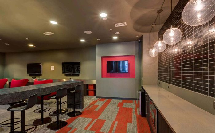 Chic communal area with vibrant red accents, stylish seating, modern countertops, and sophisticated lighting.