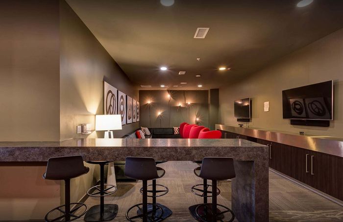 Elegant lounge area featuring plush red chairs, ambient lighting, and modern wall art for a stylish and inviting atmosphere.