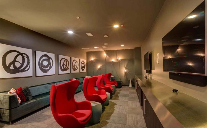 Modern entertainment room featuring sleek red chairs, elegant wall art, and ambient lighting.