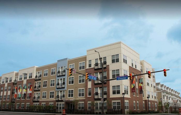Modern apartment complex with vibrant facade, featuring spacious balconies and contemporary urban design, located at a bustling street intersection.