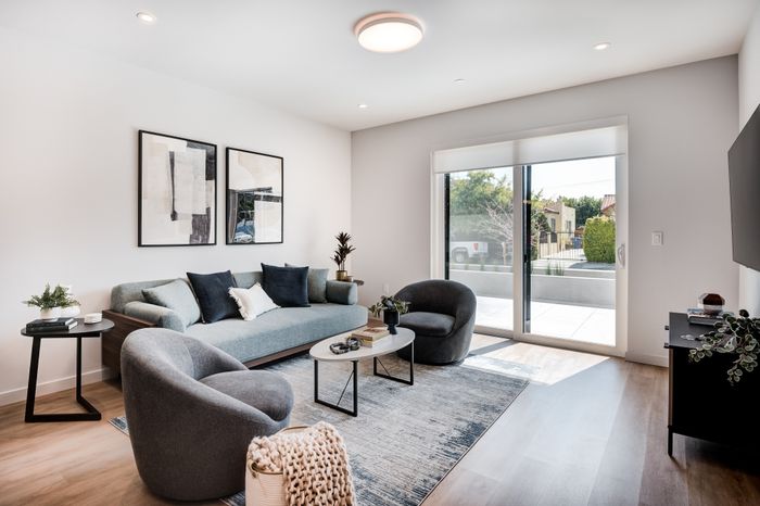 Modern living room with elegant decor, large windows, cozy seating, and abundant natural light.