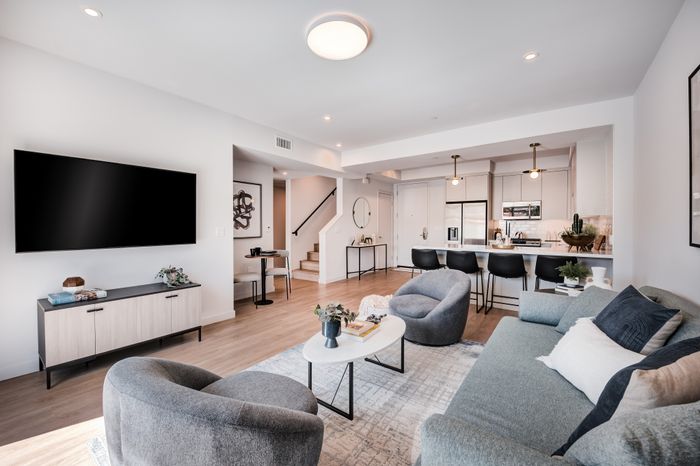 Sleek and modern open-concept living room with elegant seating, stylish decor, and a contemporary kitchen featuring minimalist design.