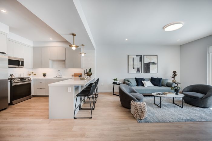 Chic open-concept living space featuring a modern kitchen with sleek appliances, elegant breakfast bar, and a cozy living room area with stylish furnishings.